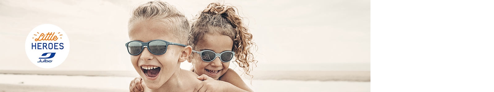 Un garçon et une fille jouant à la plage et portant des lunettes de soleil Julbo